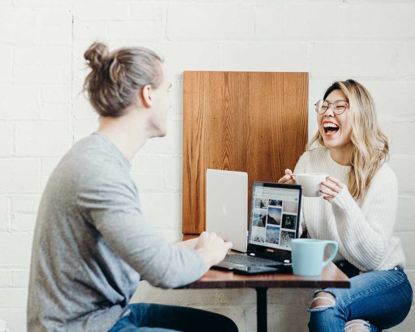 home-hero-bg.jpg alt="Specialist casually accepting a client order while working on a laptop, with a colleague laughing nearby"